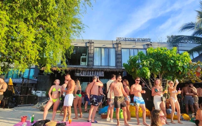 Customers in swimwear outside Andaman Genetics Koh Phi Phi, enjoying a beachfront cannabis dispensary experience