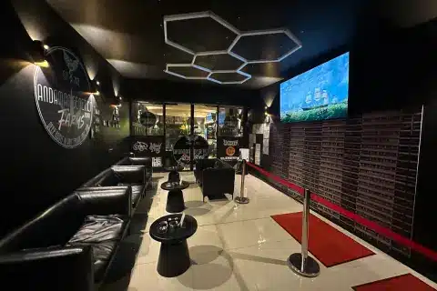Interior of the Andaman Genetics lounge in Ao Nang, Krabi, with black leather sofas, a large sports TV and modern lighting.