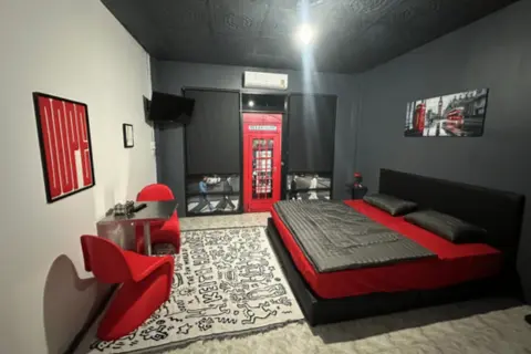 Guest room at Andaman Genetics in Ao Nang, Krabi, featuring a double bed, red seating, air conditioning and a private dining area.